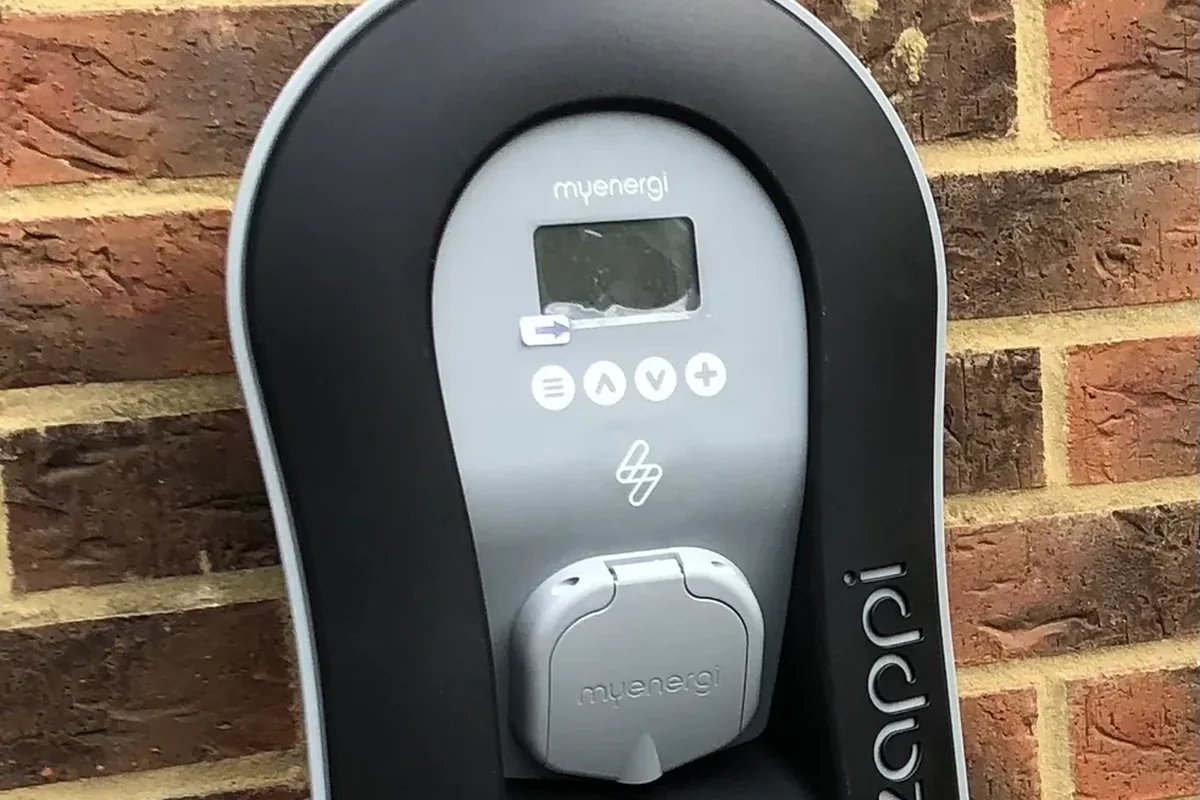 Close-up of a black untethered Zappi EV charger on brick