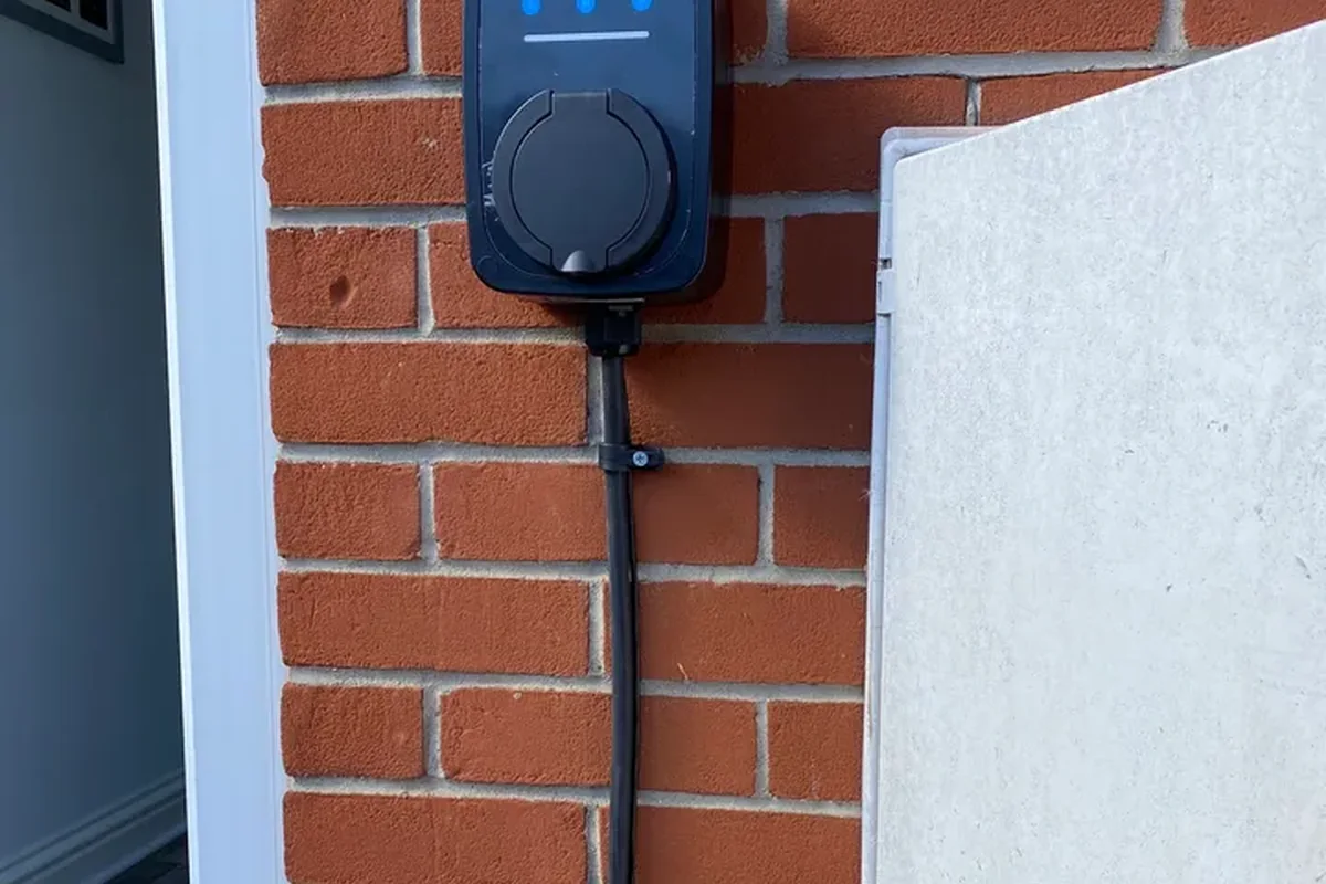 Ohme charger on brick with the cable clipped neatly down to a socket