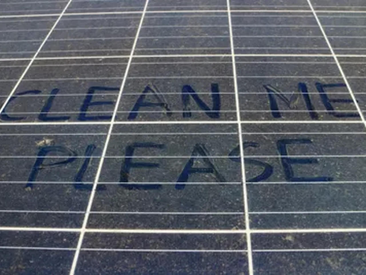 Dirty solar panels with clean me please written in the dust